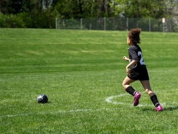 Imagen de archivo de un niño corriendo en un campo de fútbol