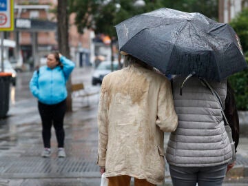 Dos personas se refugian de la lluvia con un paraguas 